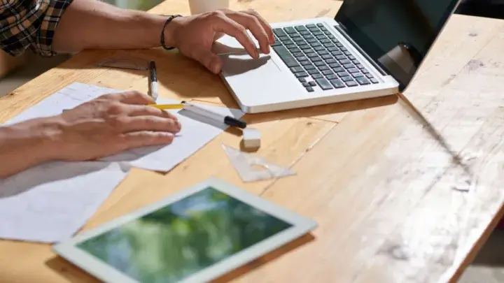 Engineer working on laptop and sketching a project